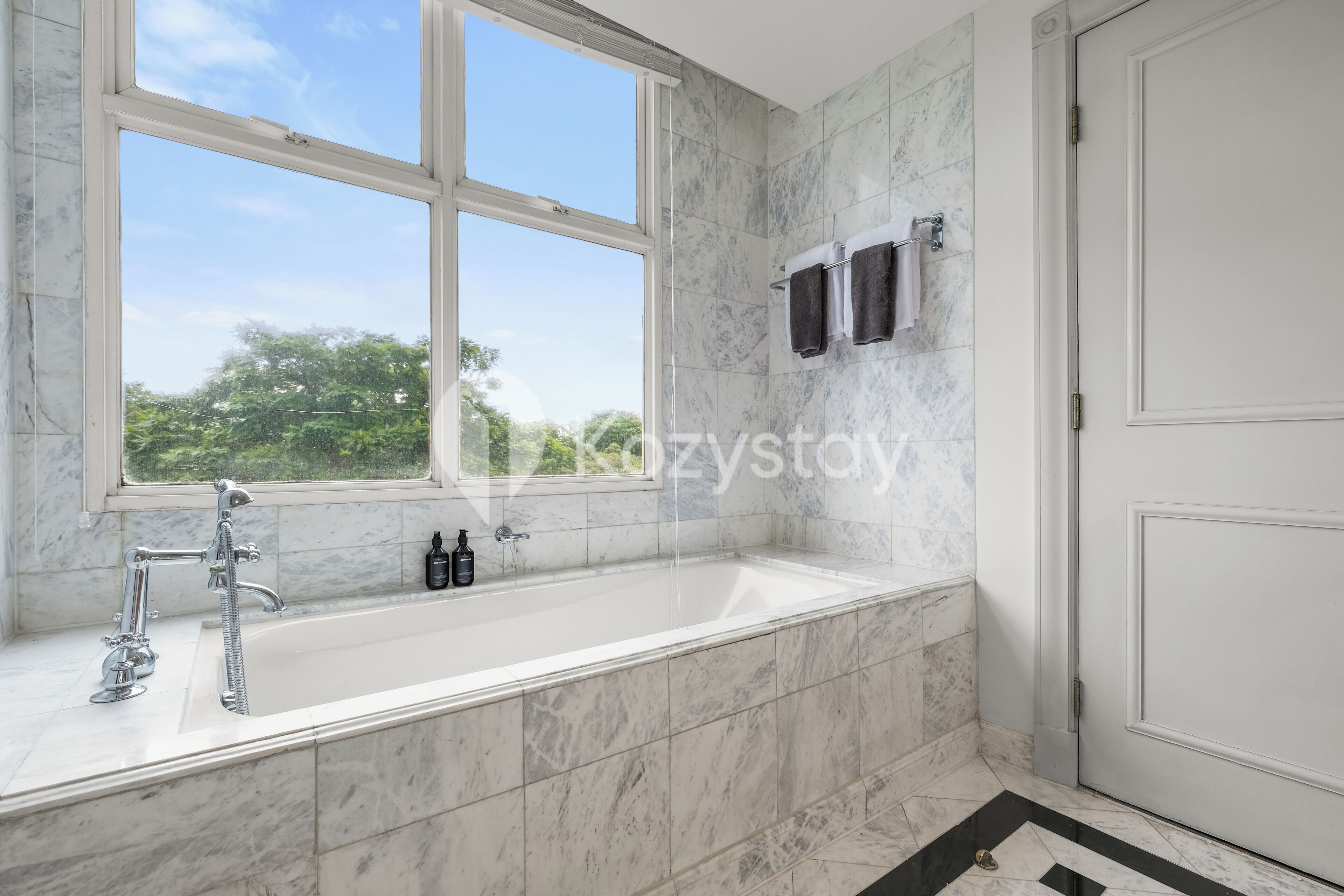 A modern bathroom with a large bathtub, a window, and a towel rack.