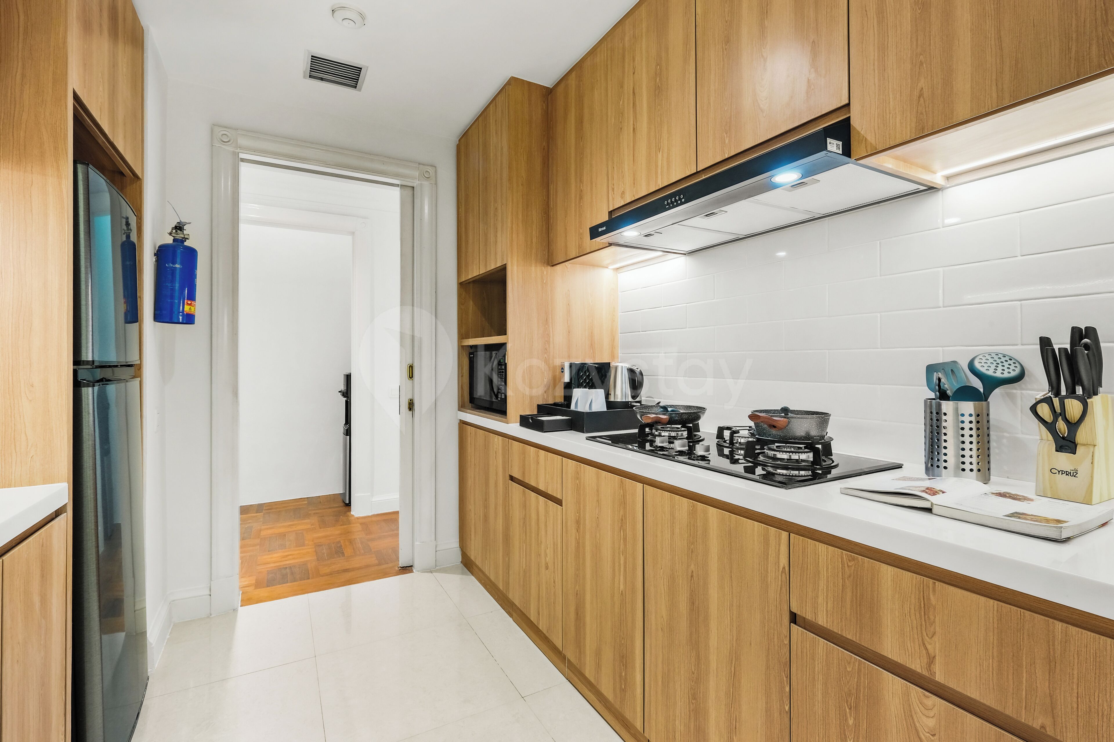 Una cucina moderna con mobili in legno, un piano di lavoro bianco e un piano cottura integrato.