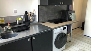 A compact kitchen with a sink, a microwave, a built-in oven, and a washing machine. - Stylish flat in Chesterfield near Peak District (Chesterfield)