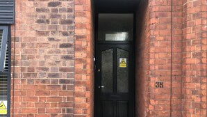A black door with a CCTV warning sign, a doormat, and a number 35 on the wall. - Stylish flat in Chesterfield near Peak District (Chesterfield)