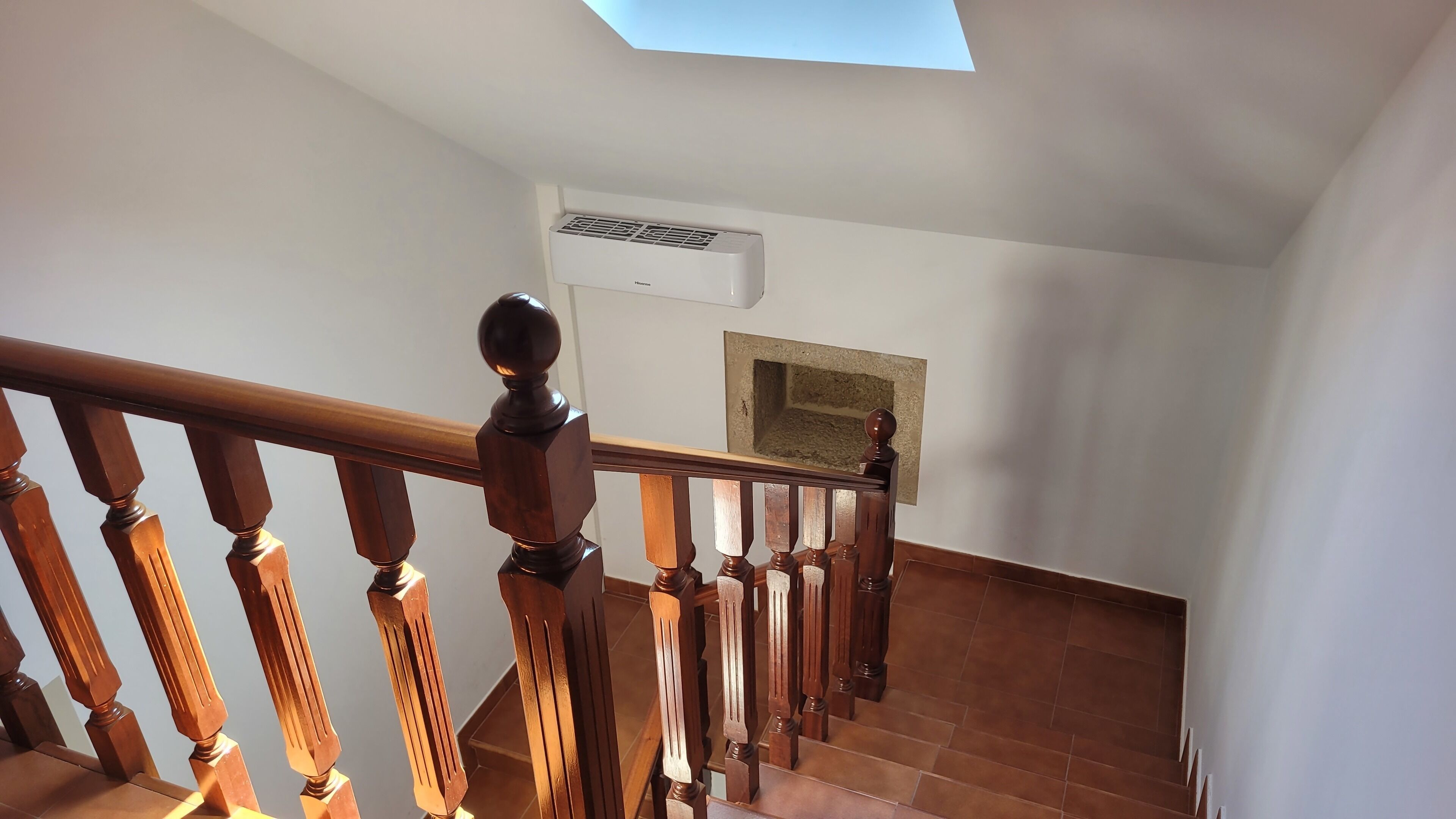 A staircase with wooden balusters and a modern air conditioning unit mounted on the wall.