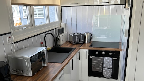 A compact kitchen with a microwave, toaster, kettle, and oven. There is a wooden countertop, a sink, and a chair. - Seaside Chalet Escape in Bridlington (Bridlington)