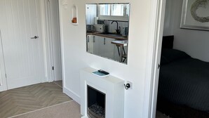 A modern living room with a fireplace, a sofa, and a kitchen area visible through an open door. - Seaside Chalet Escape in Bridlington (Bridlington)
