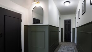 A hallway with dark doors, a mirror, and a patterned carpet. - King Size Bed, Near Hwy, Work Desk, Parking Just A Few Feet Away (Lockport)