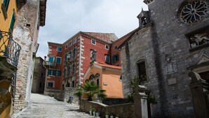 Una calle estrecha con una escalera de piedra que conduce a un edificio de fachada roja y una torre con reloj.