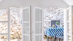 A room with a stone wall, a table with a striped tablecloth, and a chair. - La Rocca Duo - Hidden In Istria, Labin, Croatia (Labin)