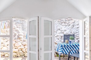 Una habitación con pared de piedra, una mesa con mantel a rayas y una silla.