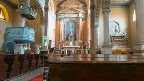 Interior de una iglesia con altar central, bancadas y una gran pila bautismal.