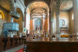 Interior de una iglesia con altar central, bancadas y una gran pila bautismal.
