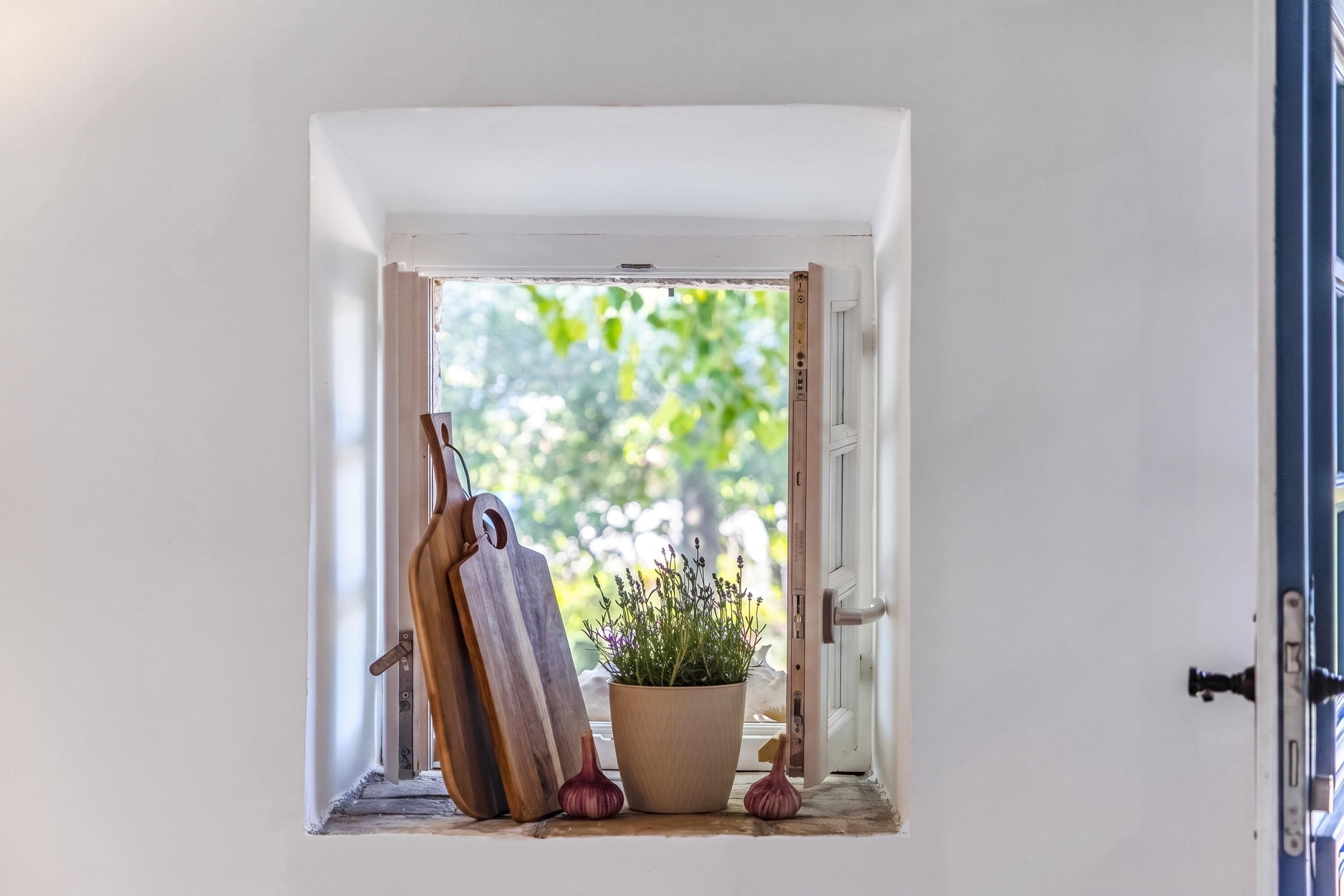 Ein Durchgang zu einem kleinen Fenster mit einer Holzschneidebrett und einem Blumentopf.