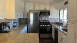 A kitchen with white cabinets, a stainless steel refrigerator, a microwave, a stove, and a dishwasher.