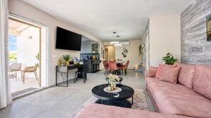 En moderne stue med sofa, sofabord og et spiseområde med stole og bord.
