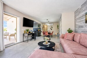 A modern living room with a sofa, coffee table, and a dining area with chairs and a table.