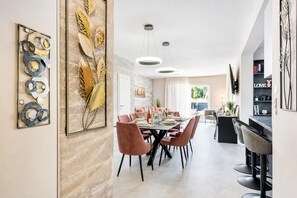 A modern dining area with a large table, multiple chairs, and pendant lighting.