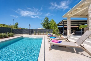 A swimming pool with lounge chairs and a covered patio area. - Villa Aria with heated Pool and Whirlpool, Poreč, Croatia (Poreč)
