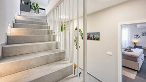 En moderne trappe med et minimalistisk design, der fører op til et værelse med en seng og et billede på væggen.