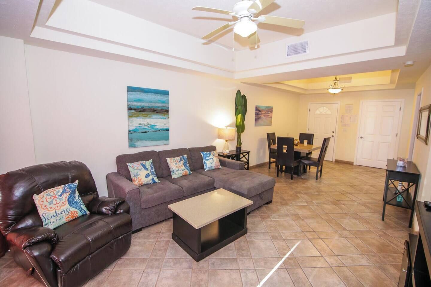 A living room with a sofa, coffee table, and a dining area with chairs and a table.