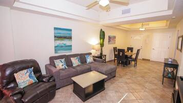 A living room with a sofa, coffee table, and a dining area with chairs and a table.