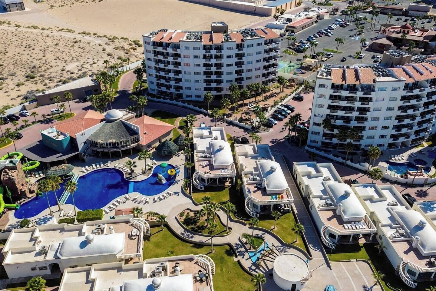Un complexe hôtelier comprenant plusieurs immeubles de grande hauteur, une piscine centrale et un espace paysager agrémenté de palmiers.