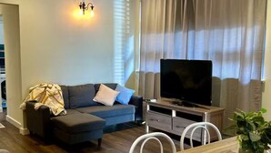 Un salon moderne avec un canapé, un téléviseur, une table à manger et un ventilateur de plafond.