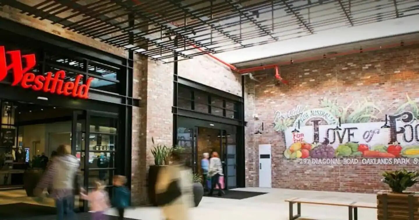 Un centro comercial Westfield con fachada de ladrillo y un gran mural que anuncia 'Love of Food'.