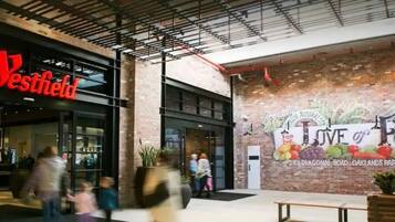 Un centro comercial Westfield con fachada de ladrillo y un gran mural que anuncia 'Love of Food'.