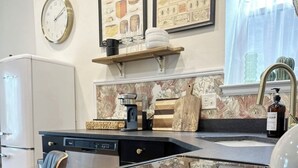 Une cuisine équipée d’un réfrigérateur, d’une machine à café, d’un évier et d’une horloge murale.