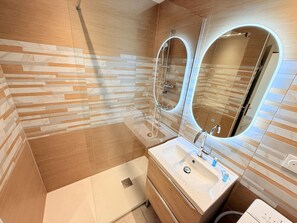 A modern bathroom with a shower, a sink, and a mirror.