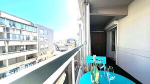 A balcony with a table and chairs, a bottle, and two wine glasses.
