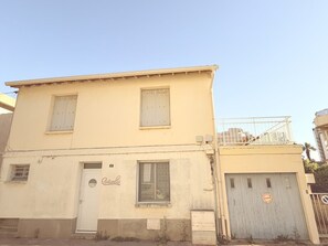 Un bâtiment à deux étages, doté d’une façade plate, d’une porte de garage et d’un balcon avec une balustrade.