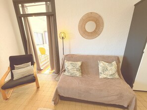 Ein Zimmer mit einer Couch, einem Sessel, einer Lampe und einer Wanddekoration.
