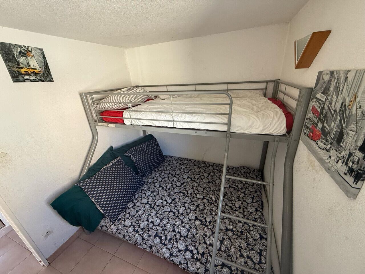 Habitación con literas, una inferior y otra superior. Encima de la litera superior hay un cuadro enmarcado.