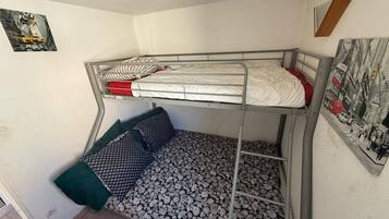 Habitación con literas, una inferior y otra superior. Encima de la litera superior hay un cuadro enmarcado.