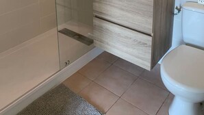 A modern bathroom with a glass-enclosed shower, a wooden vanity with a sink, and a toilet. - Côté Sud - Swimming pool, BBQ and CLIM (Vic-la-Gardiole)