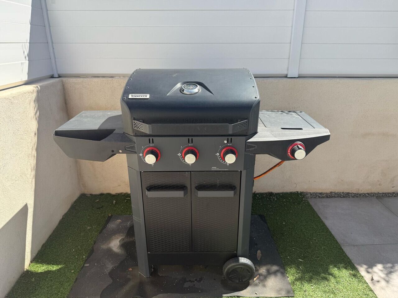 Un barbecue d’extérieur noir doté de quatre boutons de contrôle, d’un écran numérique et d’une étagère latérale.