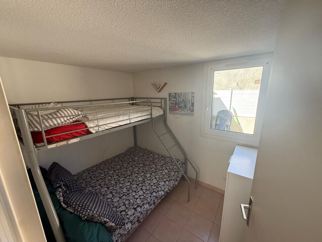 Una camera del dormitorio con letti a castello, una piccola finestra e una porta.