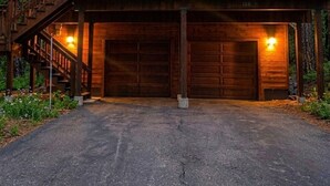 Une cabane en rondins à deux étages, dotée d’un balcon, d’un garage et d’une allée.