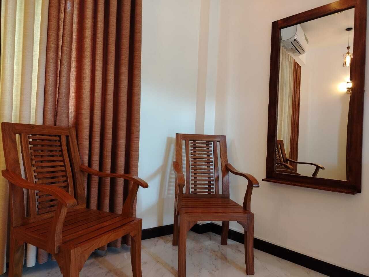 Two wooden chairs with slatted backs and armrests, positioned in front of a wall with vertical stripes and a large mirror reflecting the room.