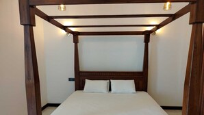 Una cama con dosel de madera y cabecera, con dos almohadas y una colcha blanca.