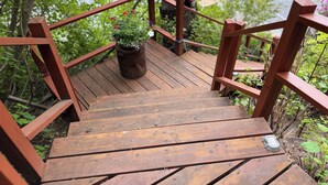Een houten trap met een leuning die uitkomt op een terras aan een waterpartij.