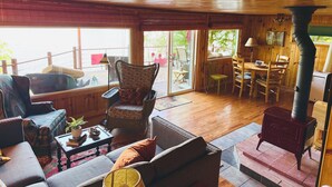 Een gezellige woonkamer met een open haard, houten vloeren en grote ramen.