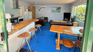 Un espace de vie compact comprenant un coin cuisine, un coin repas et un espace détente avec vue sur l’extérieur.