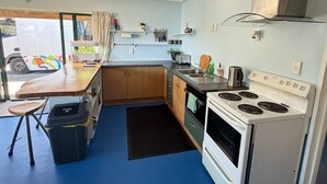 Une cuisine de taille réduite, équipée d’une cuisinière, d’un évier et de meubles de rangement en bois.