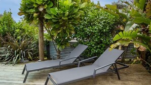 Une terrasse en bois avec deux fauteuils de jardin gris.