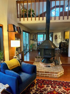 A cozy living room with a blue sofa, a fireplace, and a view of the outdoors.