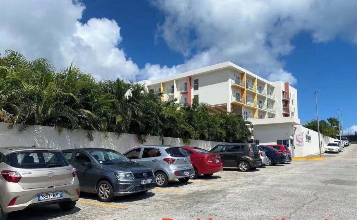 A parking lot with several cars parked in front of a building with balconies.
