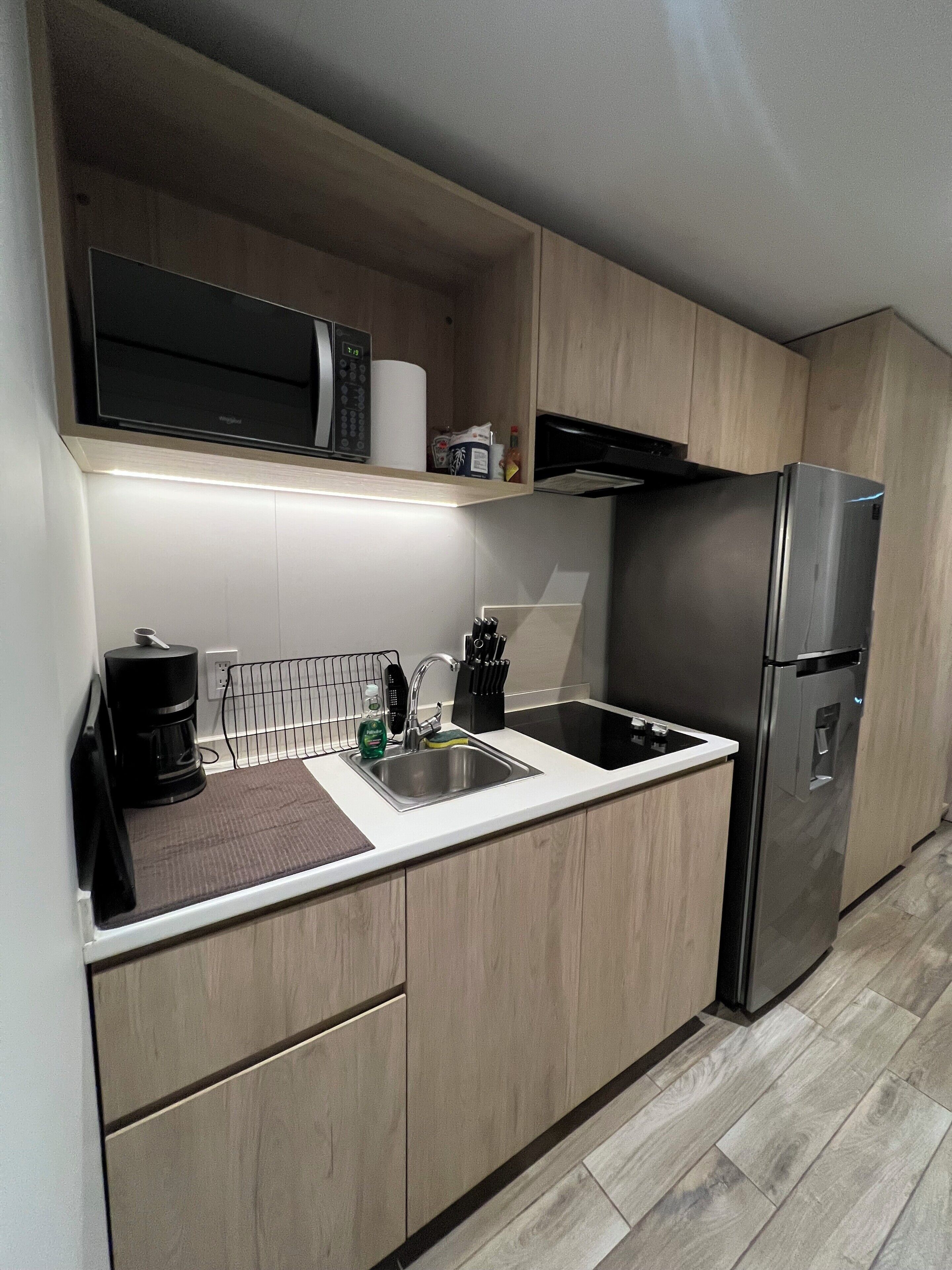 A modern kitchen with a stainless steel refrigerator, a microwave, and a coffee maker.
