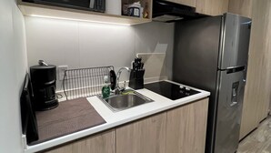 Ett modernt kök med ett kylskåp i rostfritt stål, en mikrovågsugn och en kaffebryggare.