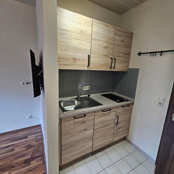Una cocina pequeña con armarios de madera, un lavamanos doble y un salpicadero de azulejos.