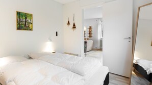 A bedroom with two beds, a painting, and a mirror.